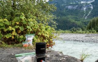 OPSAK odor-proof bags storing camp food next to a backcountry stove and river